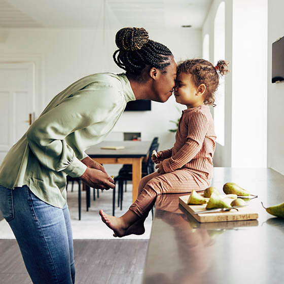 Woman and daughter smiling together in kitchen